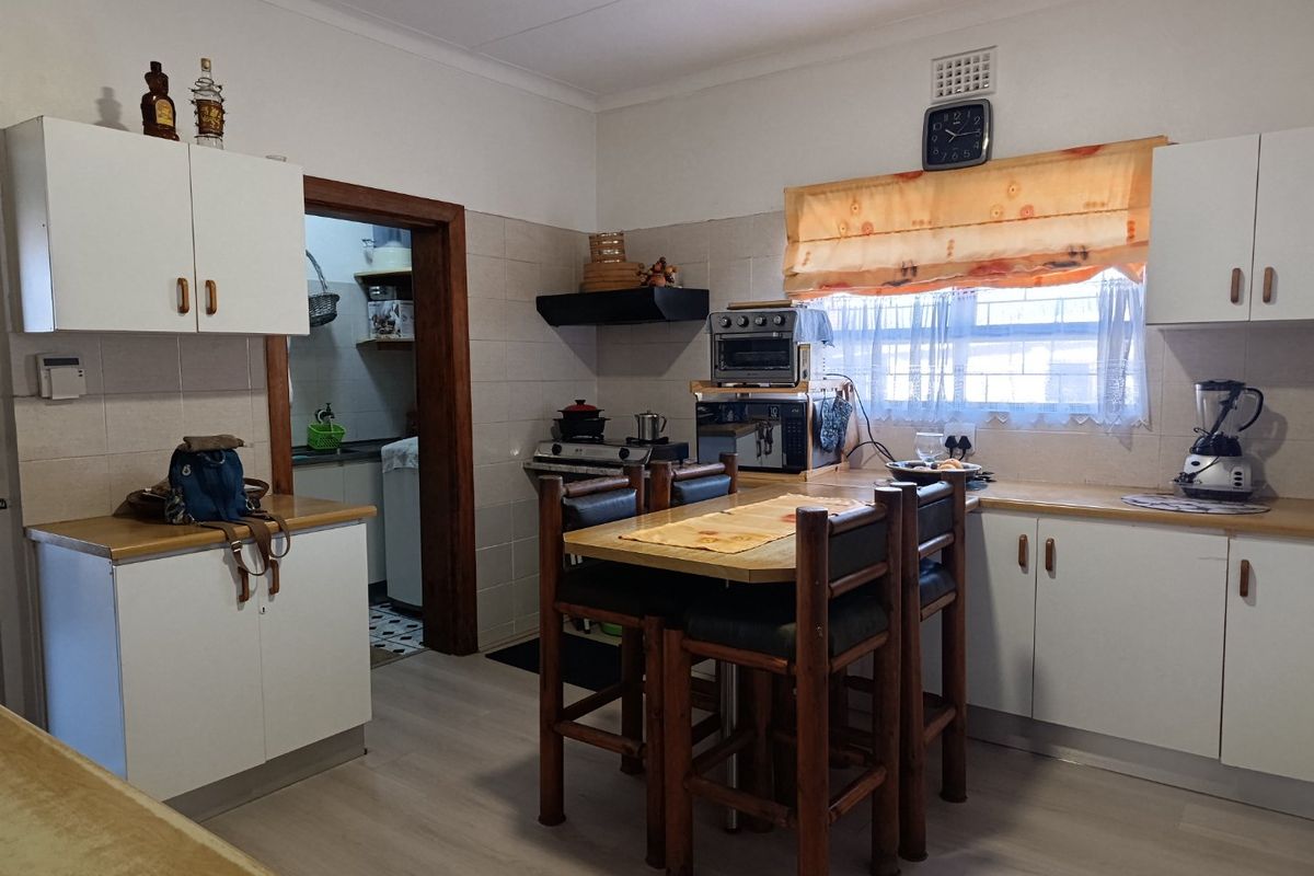 A functional kitchen featuring white cabinetry, laminate countertops, and a tiled backsplash, with an adjacent doorway leading to a secondary utility area.