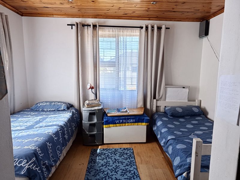 A bedroom featuring timber ceiling paneling, laminate flooring, and recessed lighting, providing a functional space with natural light through the window.