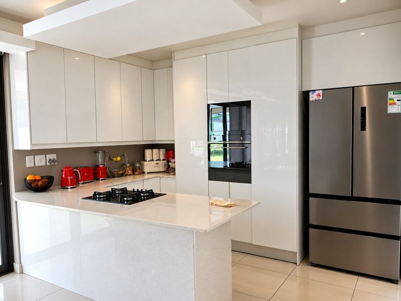 Modern kitchen featuring high-gloss white cabinetry, stone countertops, a central island with a gas hob, and integrated built-in oven.