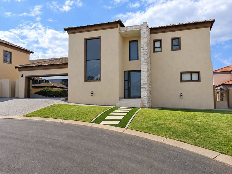 Modern double-storey residential home featuring a stone-clad entrance, paved driveway, double garage, and well-maintained front lawn.