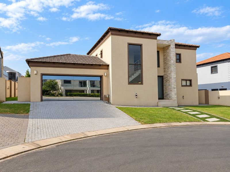 Modern double-storey residential home featuring a paved driveway, double garage, stone cladding accents, and well-maintained landscaped garden.