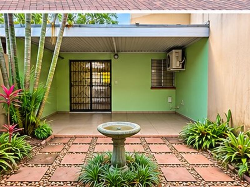 A covered patio area featuring tiled flooring, a security gate, and an outdoor paved courtyard space.