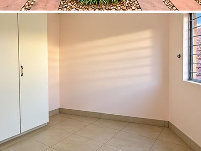 A bright, empty bedroom featuring tiled flooring, built-in cupboards, and a window with security bars.