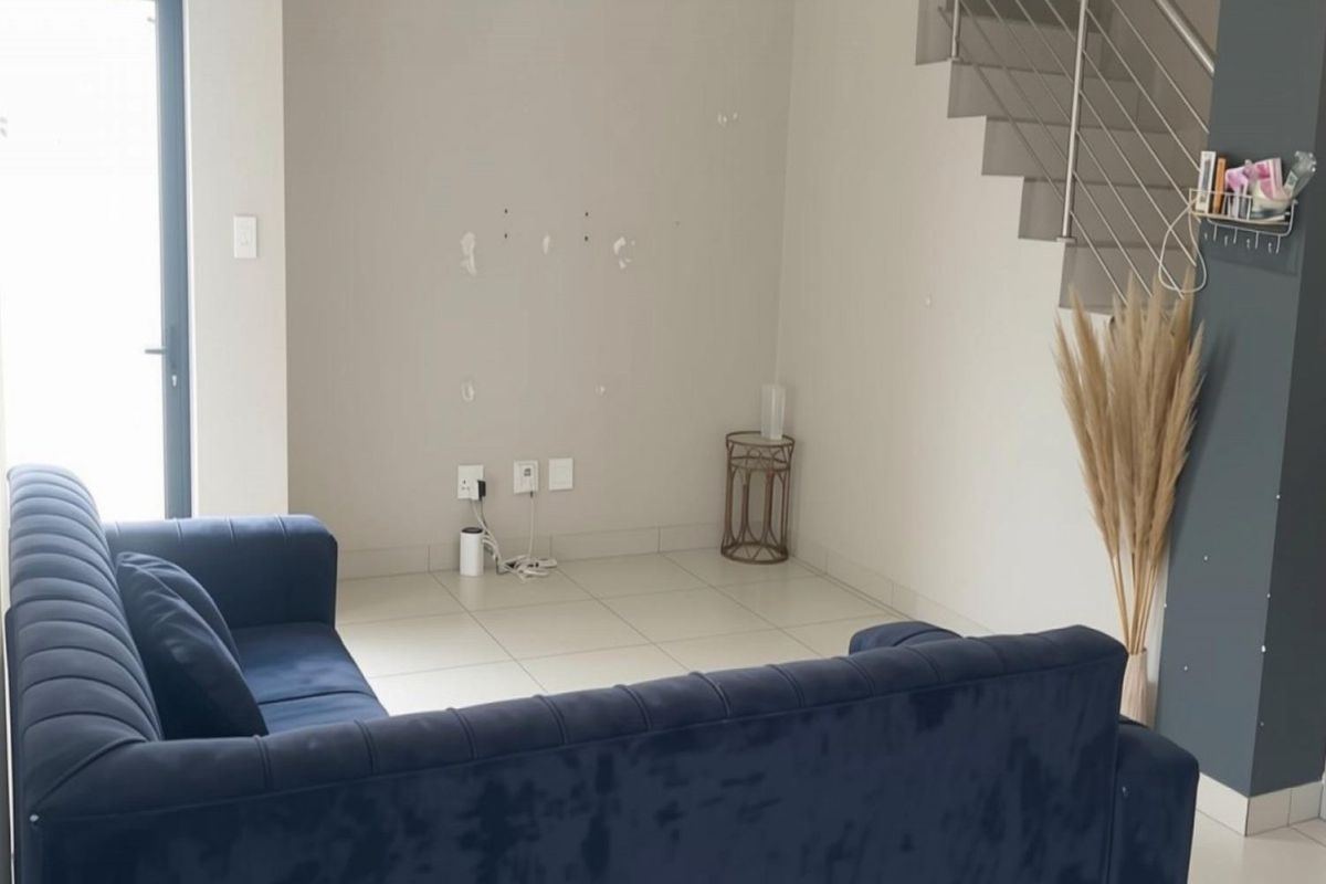 Living area featuring tiled flooring, a staircase with a stainless steel balustrade, and access to an outdoor area via a sliding door.