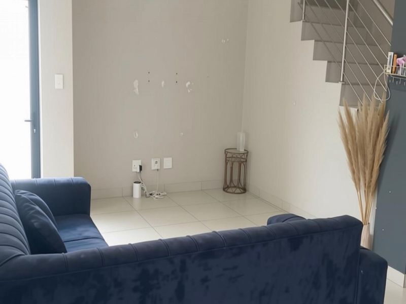 Living area featuring tiled flooring, a staircase with a stainless steel balustrade, and access to an outdoor area via a sliding door.