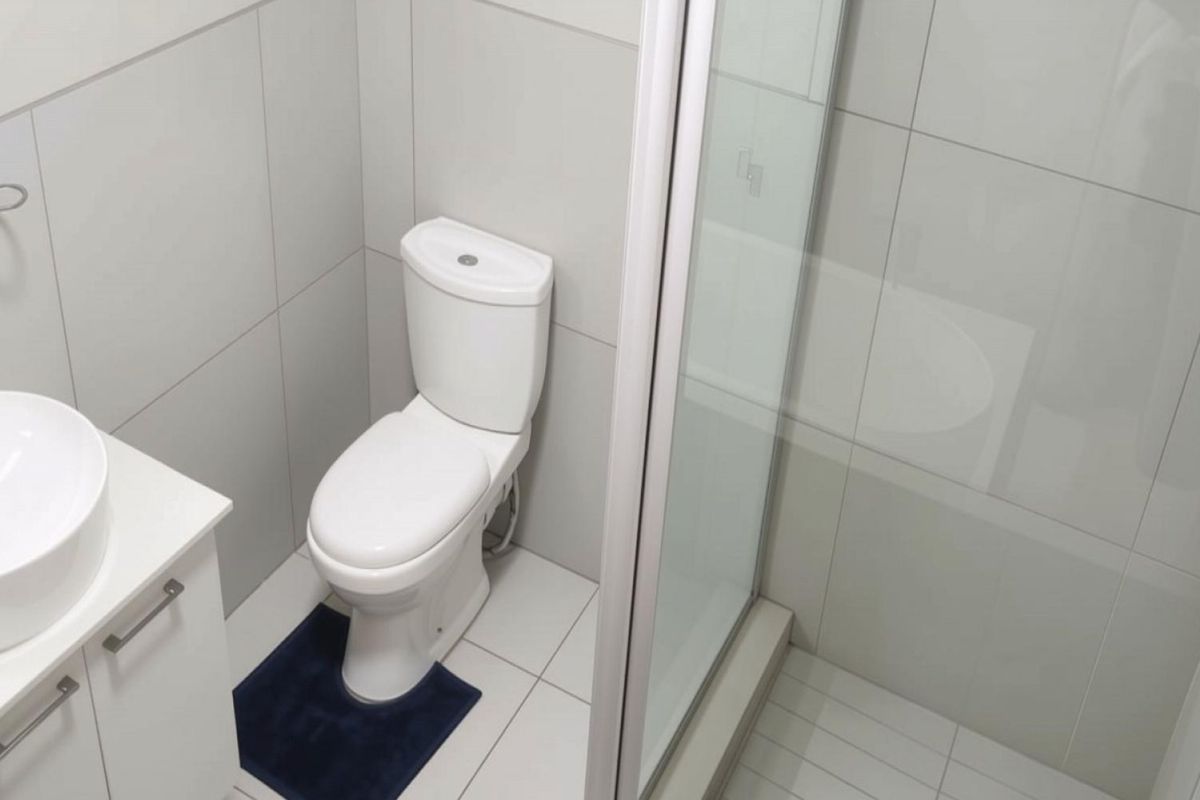 A modern, well-maintained bathroom featuring a vessel sink vanity, a standard toilet, and a glass-enclosed shower with neutral wall and floor tiling.