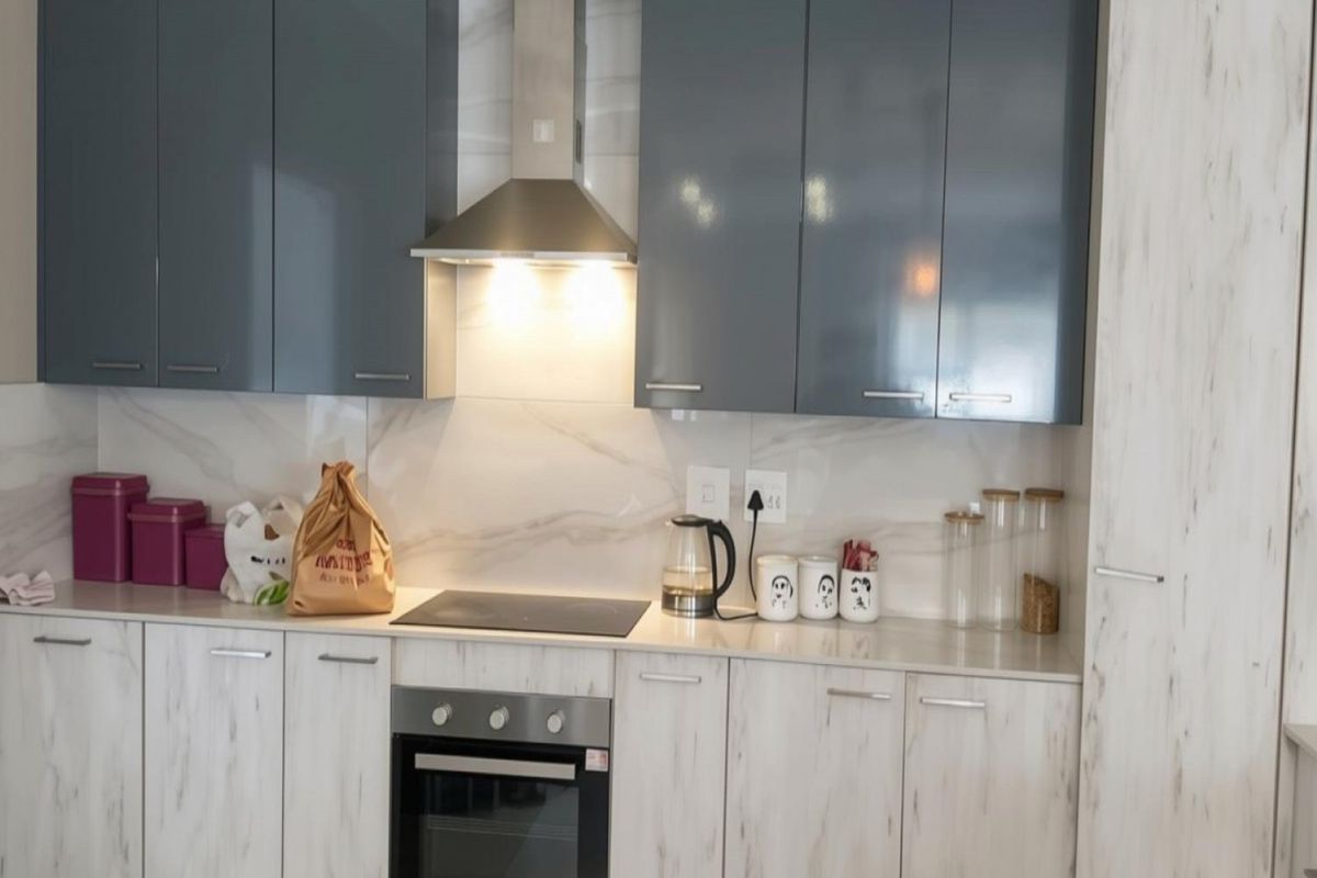 Modern kitchen featuring high-gloss grey upper cabinets, marble-effect lower cabinetry, stone countertops, and integrated stainless steel appliances.