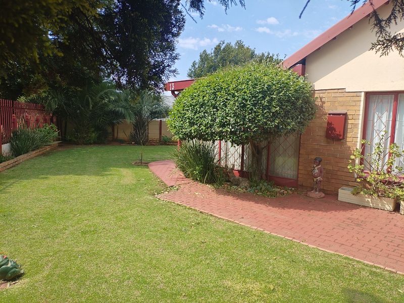 A well-maintained rear garden featuring a brick-paved pathway, established lawn, and secure perimeter fencing.