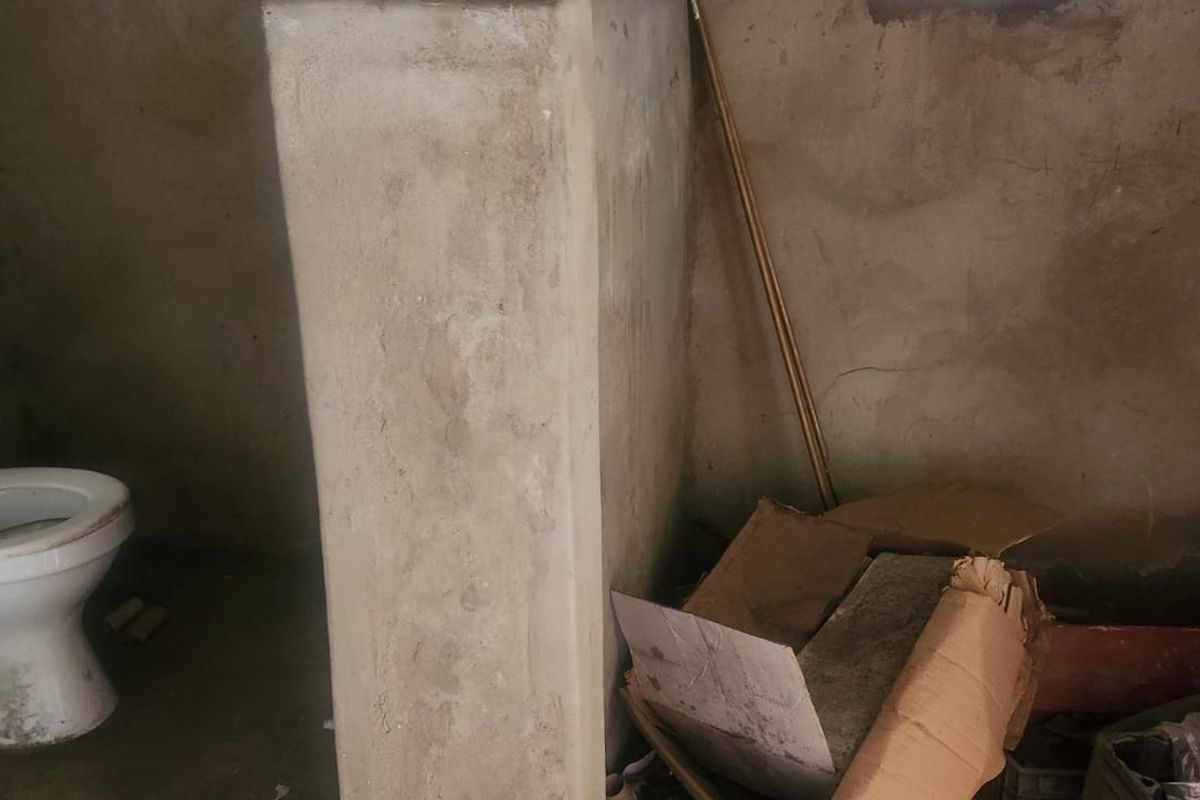 A basic bathroom space featuring a toilet, currently in an unfinished shell condition with exposed plaster walls requiring renovation and finishing.