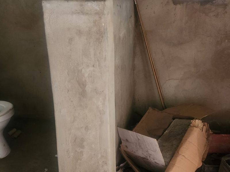 A basic bathroom space featuring a toilet, currently in an unfinished shell condition with exposed plaster walls requiring renovation and finishing.