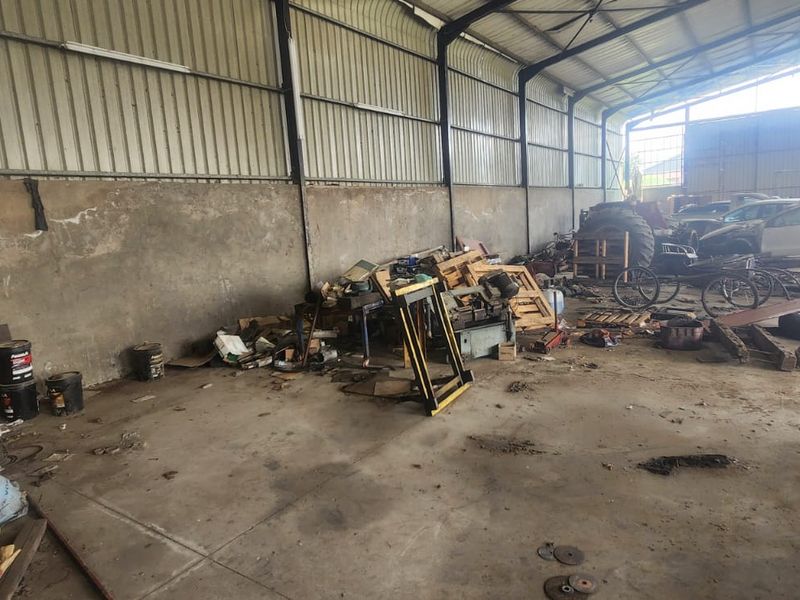 Spacious industrial utility area featuring a steel portal frame structure, corrugated metal wall cladding, and durable concrete flooring, suitable for workshop or storage use.