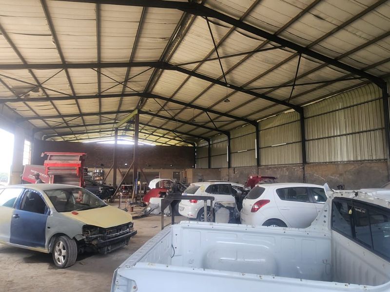 Spacious industrial warehouse featuring a steel portal frame structure, corrugated metal roofing, and concrete flooring, suitable for workshop or storage operations.