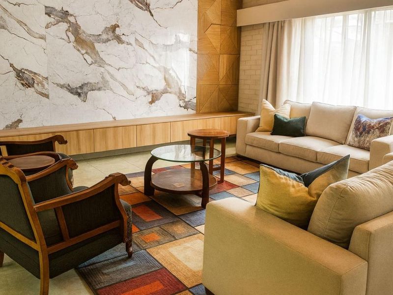 A sophisticated living room featuring a striking marble accent wall, custom built-in cabinetry, and decorative geometric wood paneling.