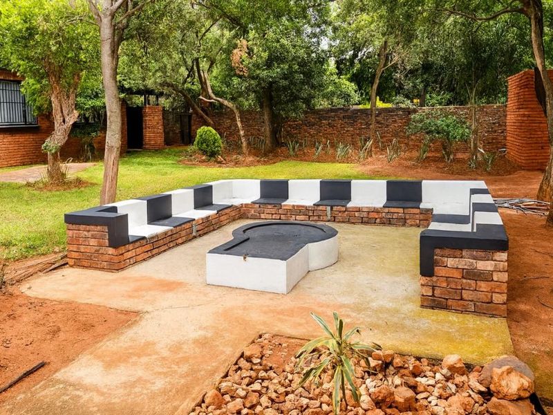 Outdoor entertainment area featuring a built-in brick fire pit and integrated bench seating, set within a private garden with mature trees.