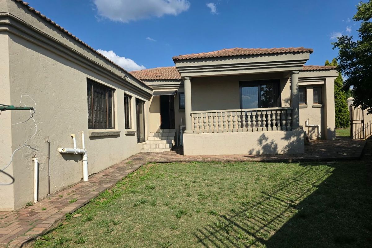 Rear view of the property featuring a covered patio with concrete columns, balustrade, paved walkway, and a small garden area.