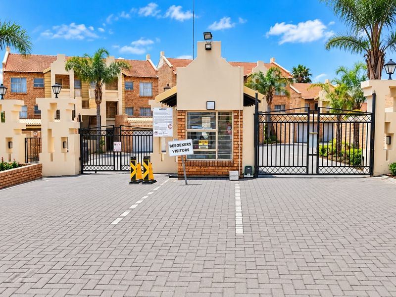 Secure gated entrance to the Havana apartment complex featuring a guard house, paved driveway, and perimeter security fencing.