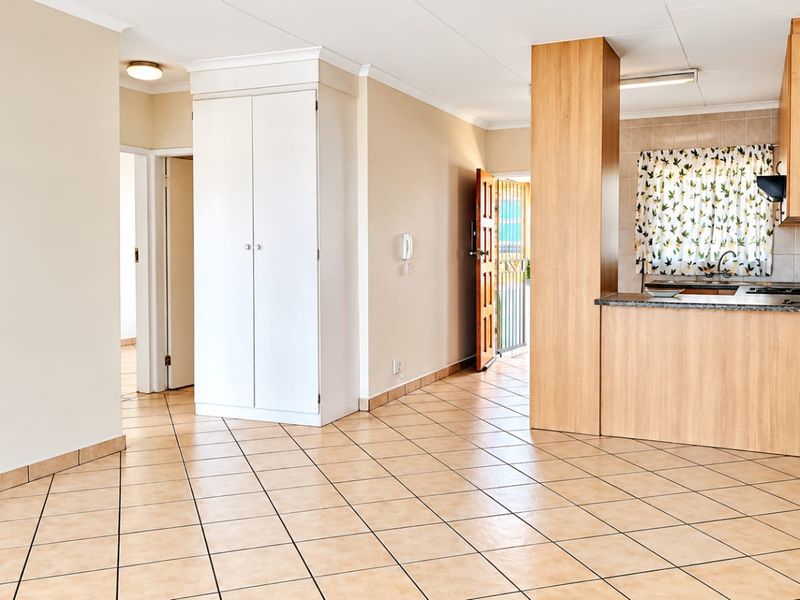 Open-plan living area featuring tiled flooring, built-in storage cupboards, and a functional kitchen space with integrated cabinetry.