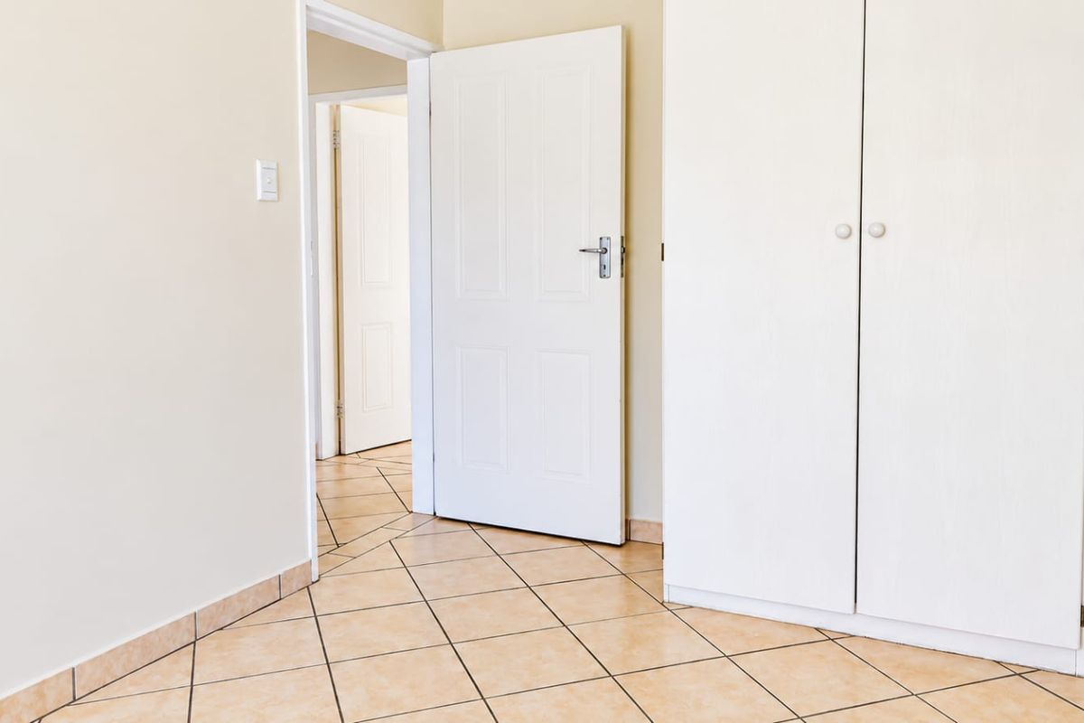 A clean, empty bedroom featuring neutral tiled flooring and built-in cupboards, offering a versatile space ready for personalization.