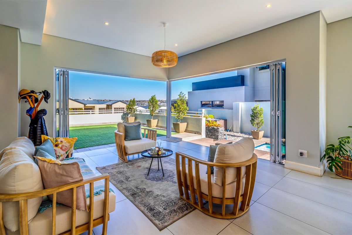 Modern living room featuring large bi-fold doors that open onto an outdoor patio area, creating a seamless indoor-outdoor flow with abundant natural light.