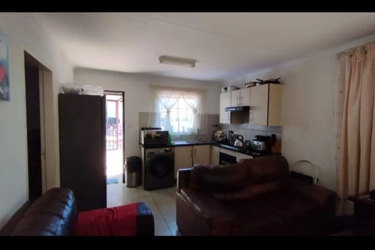 An open-plan living and kitchen area featuring tiled flooring, built-in cabinetry, and an integrated extractor fan, providing a functional combined living space.