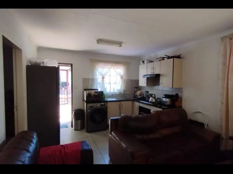 An open-plan living and kitchen area featuring tiled flooring, built-in cabinetry, and an integrated extractor fan, providing a functional combined living space.