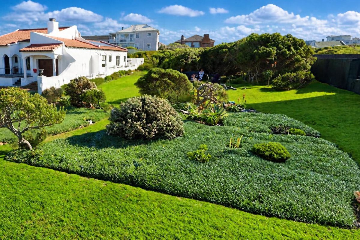 A well-maintained residential garden featuring expansive lawn areas and established landscaping, adjacent to the rear elevation of the property.