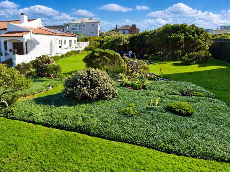 A well-maintained residential garden featuring expansive lawn areas and established landscaping, adjacent to the rear elevation of the property.