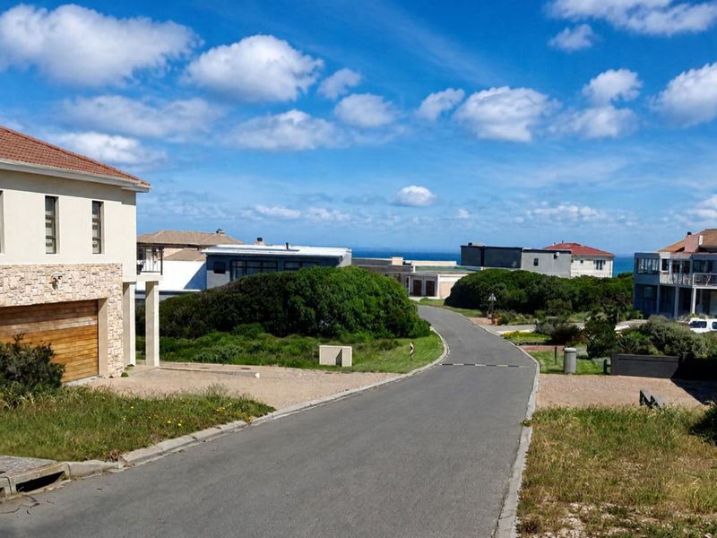 A view of the residential street and surrounding neighborhood infrastructure, showcasing the paved road, curbs, and nearby coastal residential properties.