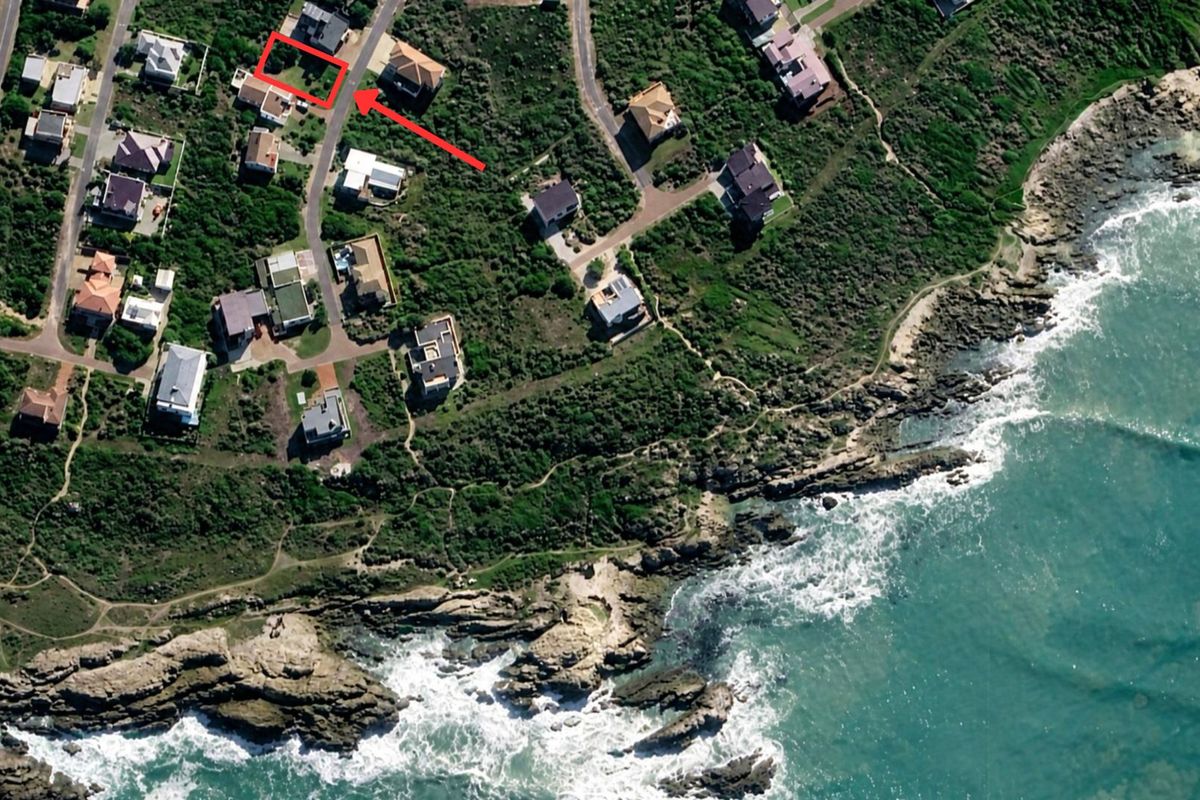 Aerial view of a residential coastal plot highlighted in red, situated in a developed neighborhood near the ocean.