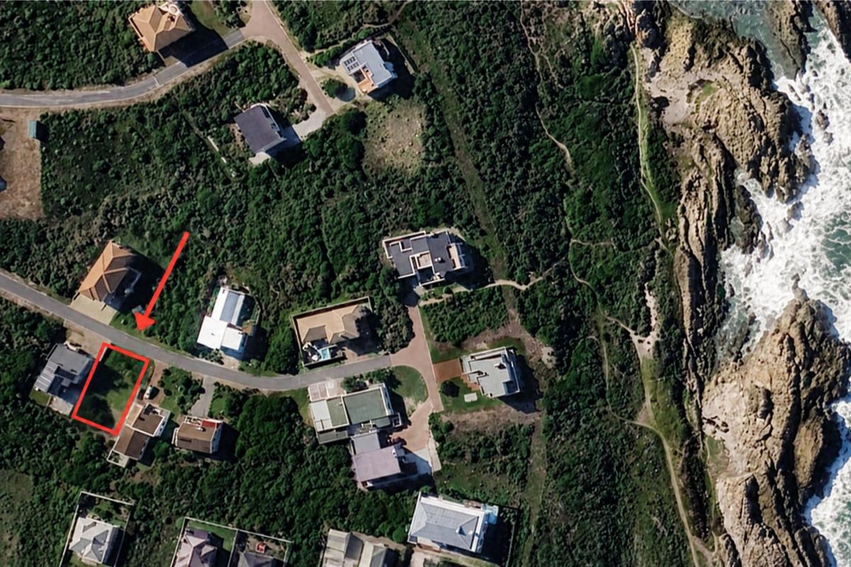 Aerial view of a vacant residential plot situated in a coastal neighborhood, highlighting its proximity to the ocean and surrounding established properties.