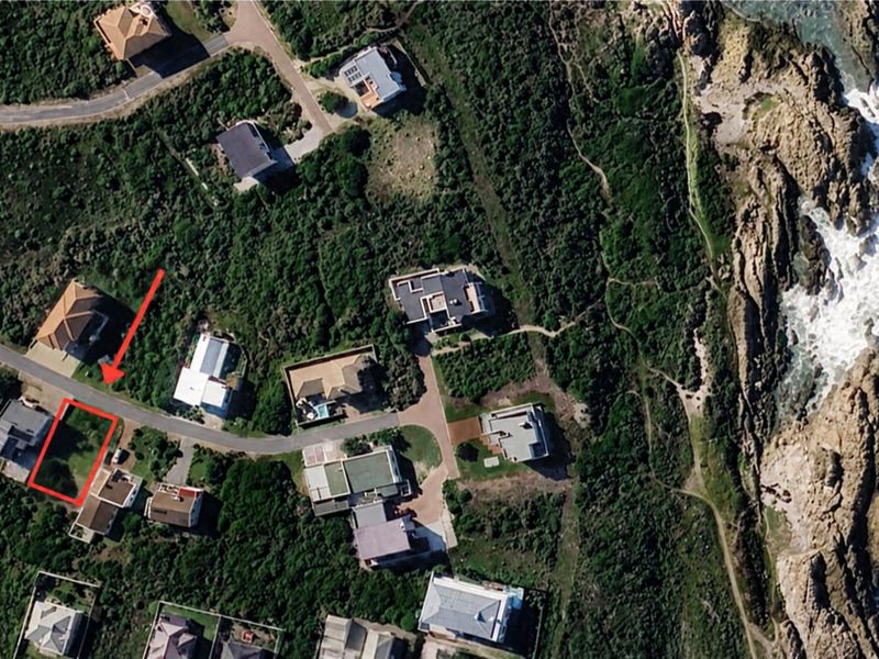 Aerial view of a vacant residential plot situated in a coastal neighborhood, highlighting its proximity to the ocean and surrounding established properties.