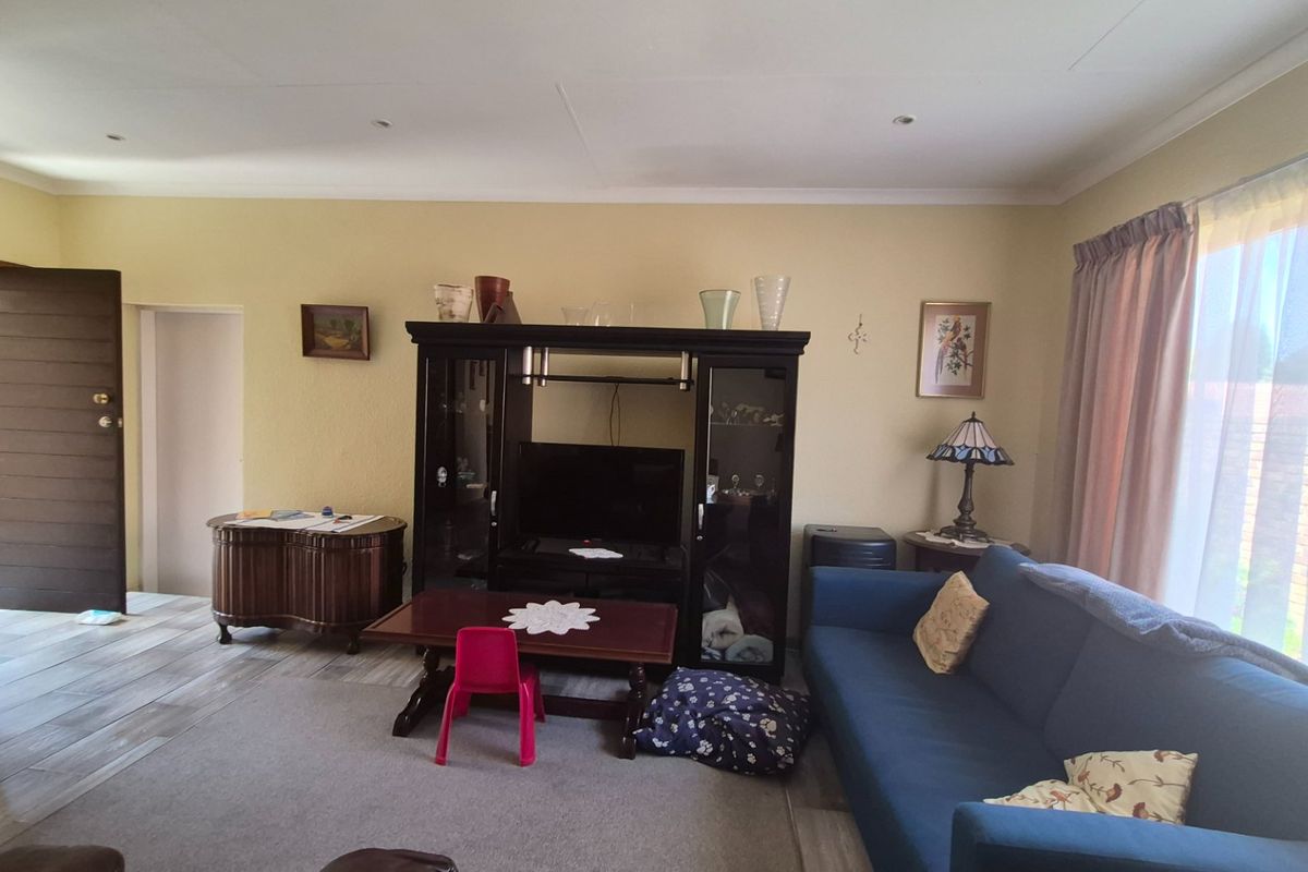 A living room featuring tiled flooring, recessed ceiling lighting, and a sliding glass door providing natural light.