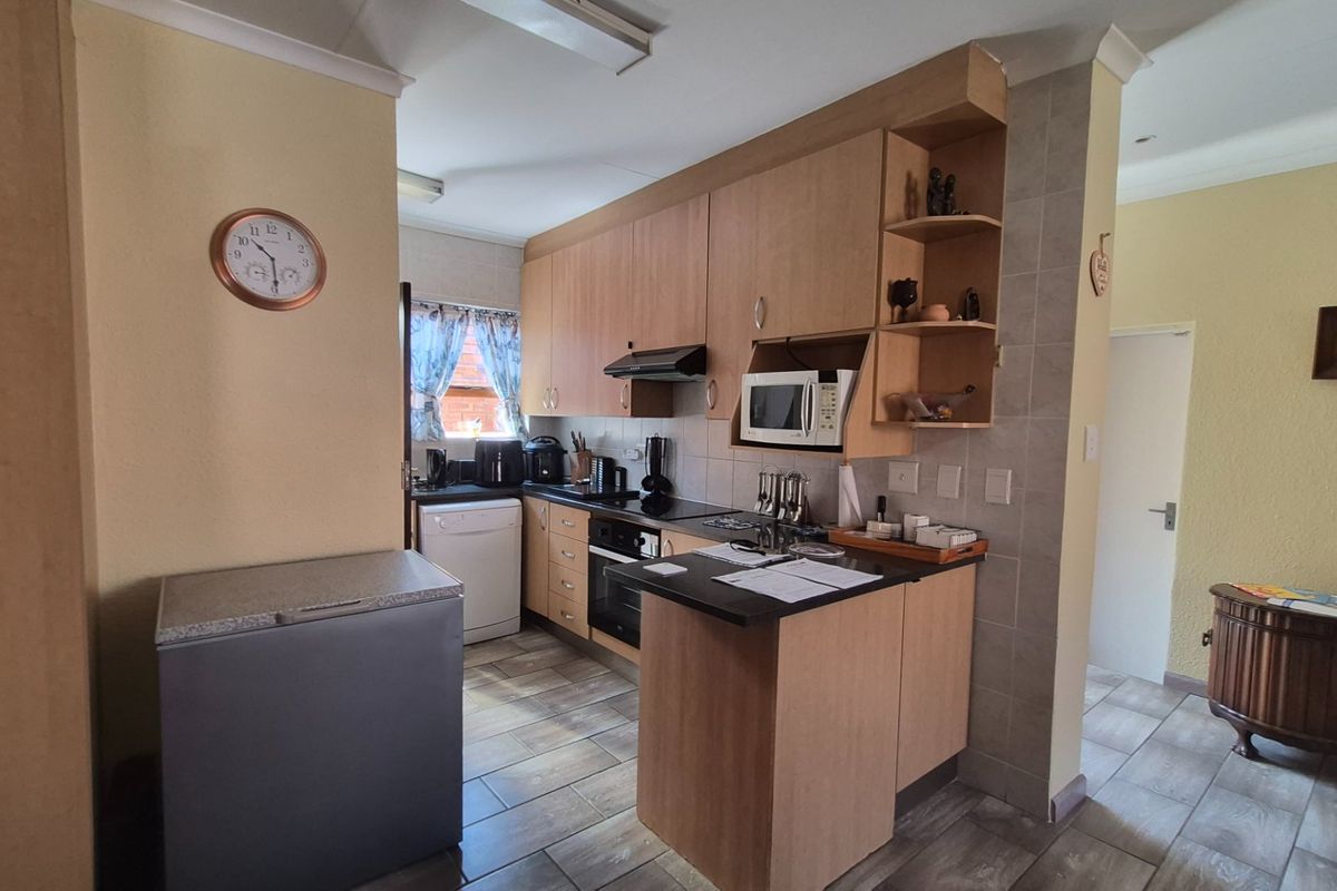 A functional kitchen featuring light wood-tone cabinetry, dark countertops, built-in appliances, and tiled flooring, offering a practical layout for daily meal preparation.