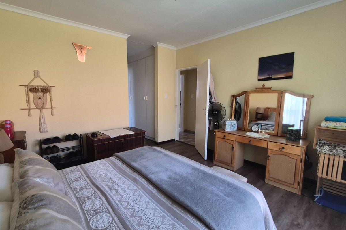 A spacious bedroom featuring laminate flooring, built-in cupboards, and coved ceilings, offering a comfortable and functional living space.