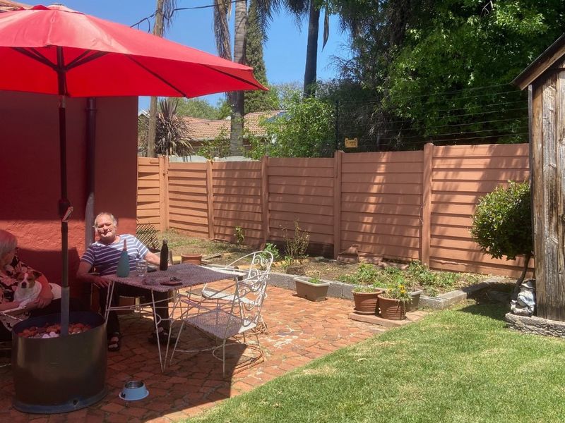 A private outdoor patio area featuring brick paving, a lawn, and a perimeter fence, providing a functional space for outdoor relaxation.