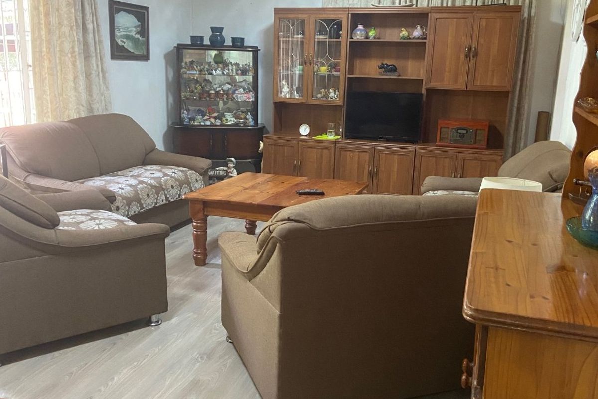 A living room featuring laminate flooring and a wall-mounted split-system air conditioner.