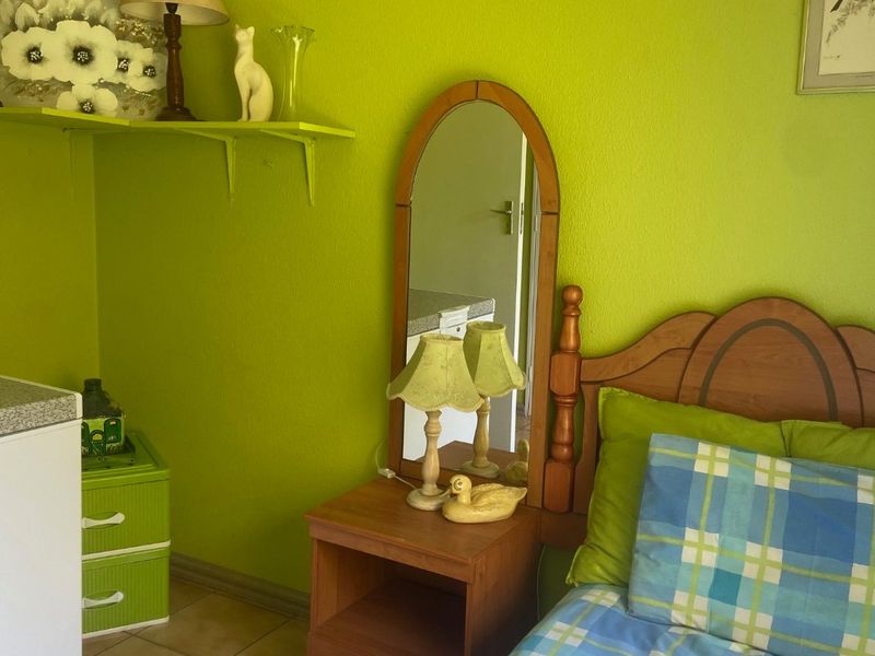 A bedroom featuring tiled flooring and a built-in wall shelf, currently finished with bright green wall paint.