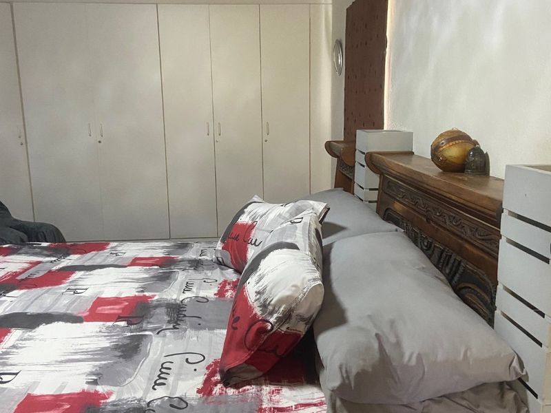 A bedroom featuring built-in cupboards, a timber ceiling, and a wall-mounted air conditioning unit.