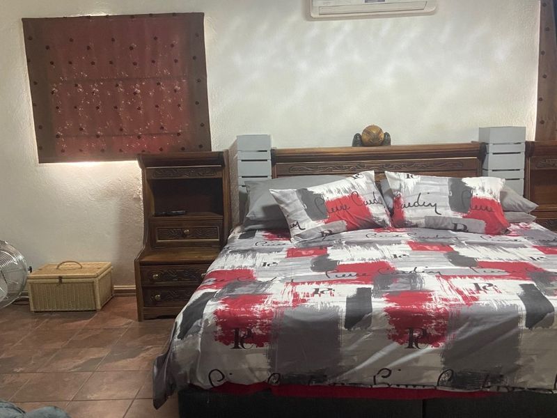 A bedroom featuring tiled flooring, a timber ceiling, and a wall-mounted air conditioning unit.