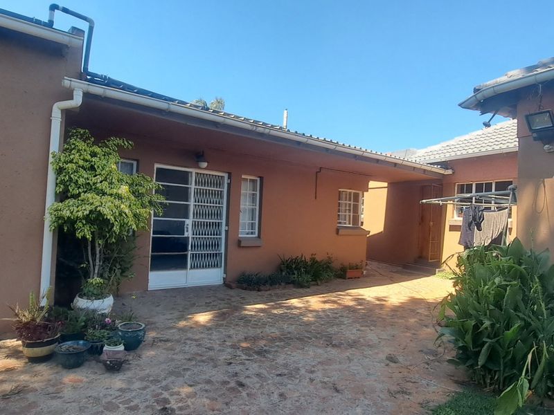 A rear courtyard area featuring paved flooring, security gates, and access to the main dwelling structure.