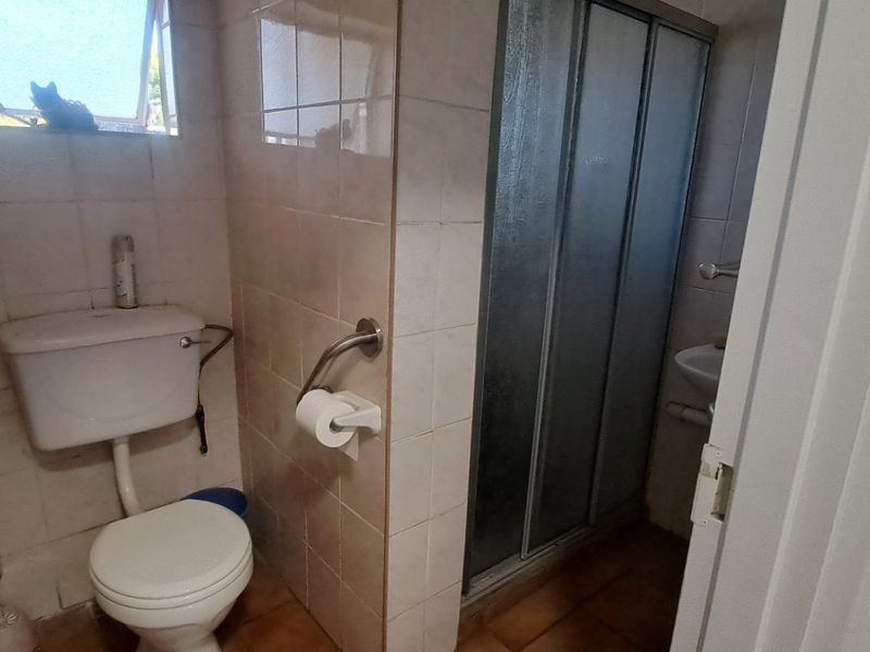 A functional bathroom featuring a shower enclosure, toilet, and tiled finishes, equipped with safety grab rails for accessibility.