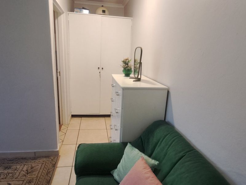 A bedroom featuring tiled flooring and a built-in cupboard, providing functional storage space.
