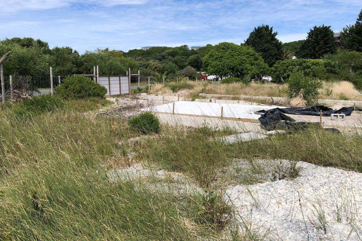 A vacant residential plot featuring a prepared concrete slab foundation, surrounded by natural vegetation and perimeter fencing, ready for development.