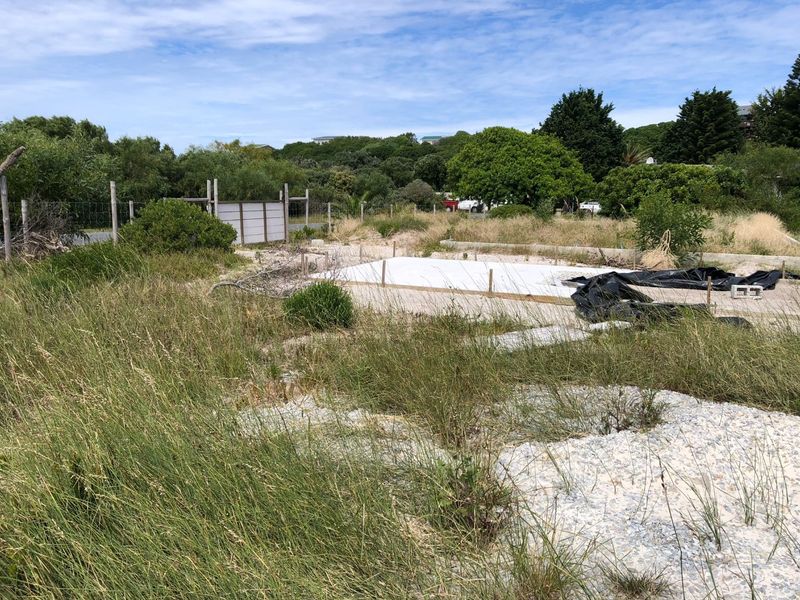 A vacant residential plot featuring a prepared concrete slab foundation, surrounded by natural vegetation and perimeter fencing, ready for development.