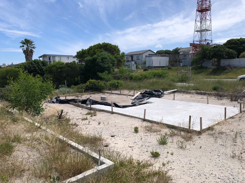 A vacant residential plot featuring an initial concrete slab foundation and wooden formwork, ready for further development.