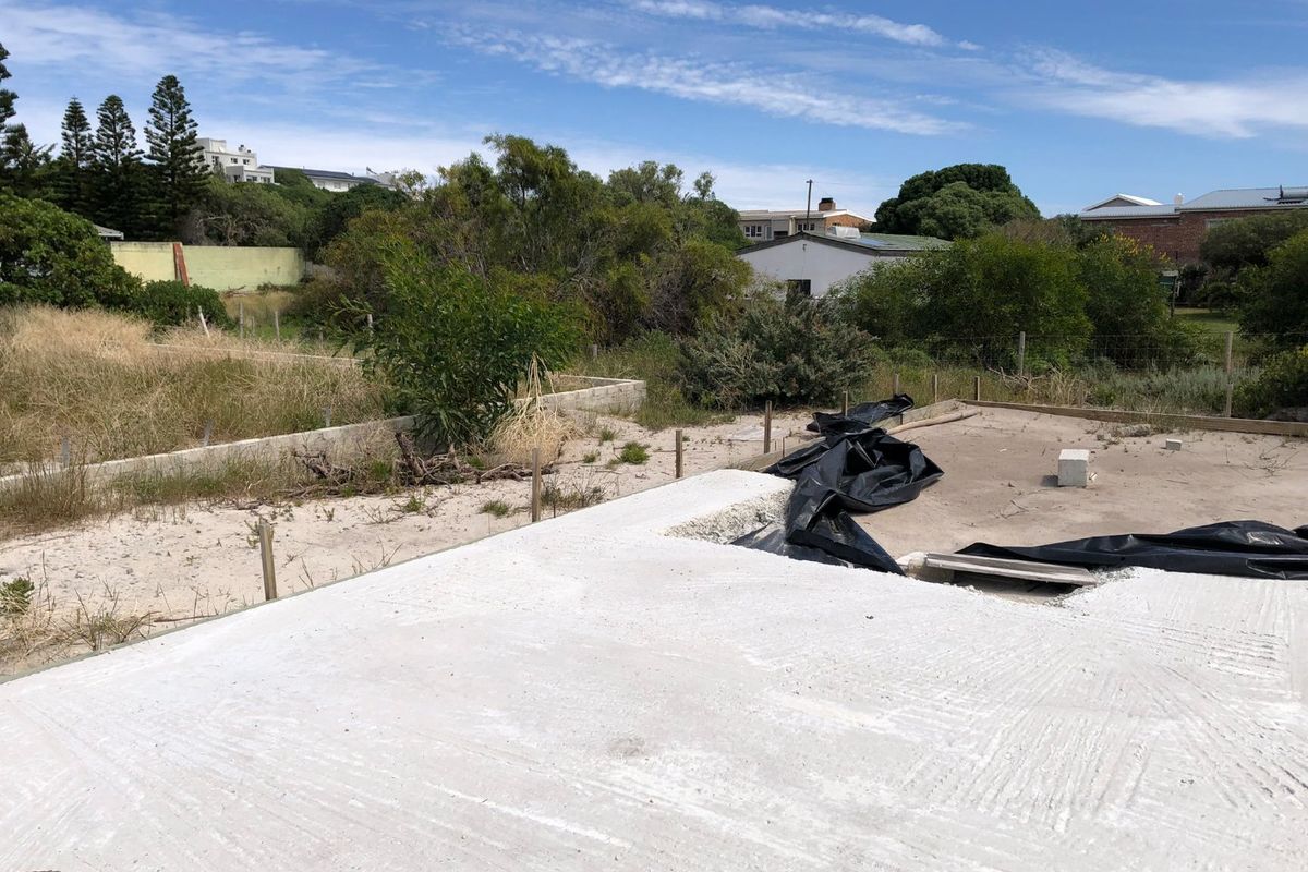 A vacant residential plot featuring a newly laid concrete foundation slab, ready for further development.