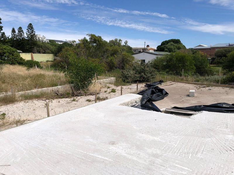 A vacant residential plot featuring a newly laid concrete foundation slab, ready for further development.