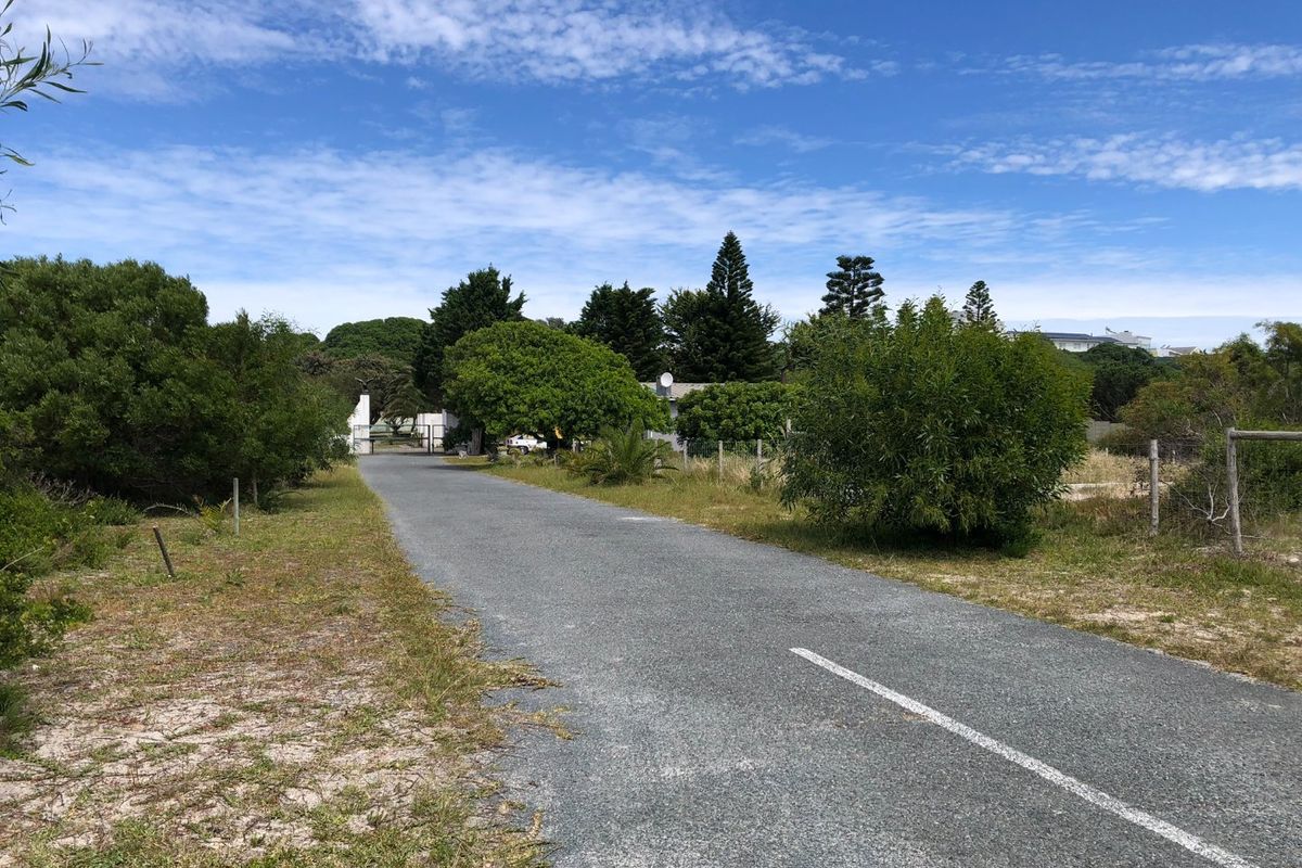A view of the paved access road leading towards the gated entrance of the residential property, surrounded by established trees and vegetation.