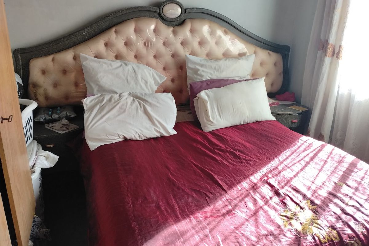 A bedroom featuring a large upholstered headboard and natural light from a side window.