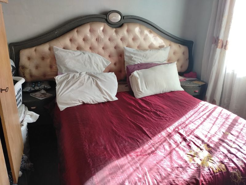 A bedroom featuring a large upholstered headboard and natural light from a side window.